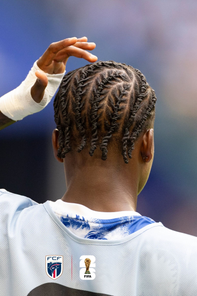 Cabo Verde football player Sidny Lopes Cabral stands on the field with his back to the camera his hand touching his head.
